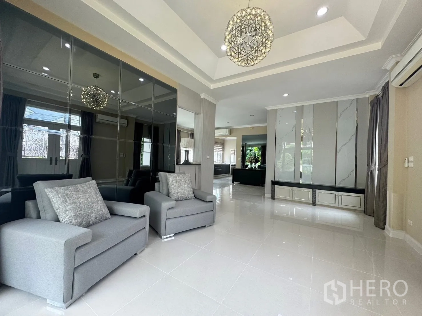 独立式住宅 出租在Prawet, Bangkok - 明亮客厅，亮面地砖、特色墙与现代吊灯。