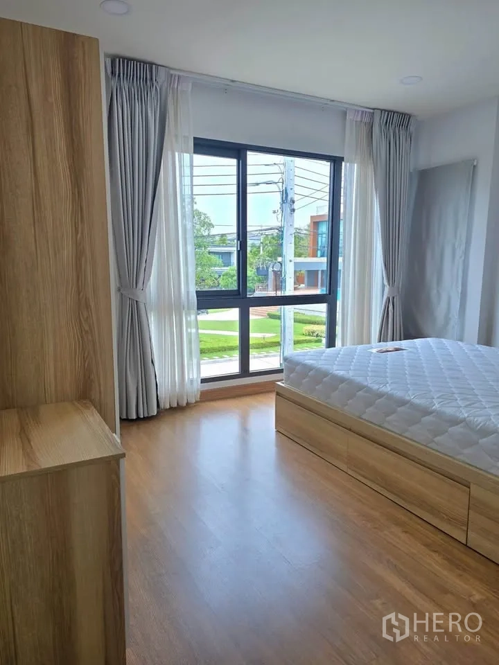 บ้านเดี่ยว for rent or sale in Bang Phli, Samut Prakan - ห้องนอนมุมกระจก พื้นไม้ และเตียงฐานลิ้นชัก