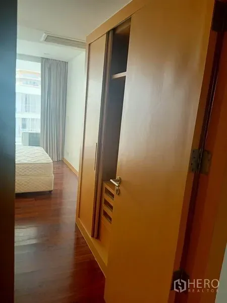 Condominium for rent in Watthana, Bangkok - Hallway with built-in wardrobe leading to a bright bedroom with window light.