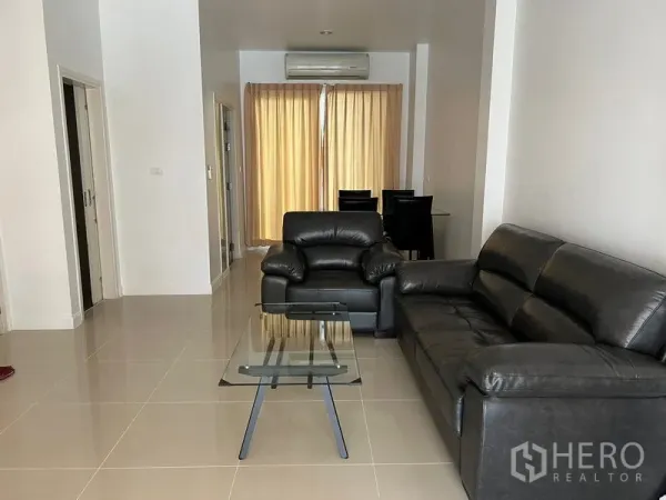 ทาวน์เฮาส์ ให้เช่าในWang Thonglang, Bangkok - ห้องนั่งเล่นสว่าง พร้อมโซฟาหนังสีดำ โต๊ะกระจก และพื้นกระเบื้อง