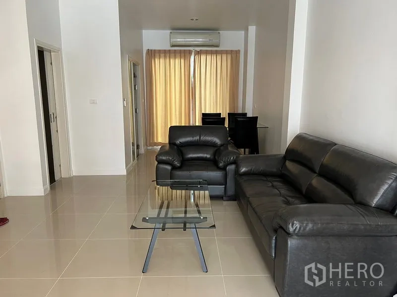 ทาวน์เฮาส์ ให้เช่าในWang Thonglang, Bangkok - ห้องนั่งเล่นสว่าง พร้อมโซฟาหนังสีดำ โต๊ะกระจก และพื้นกระเบื้อง