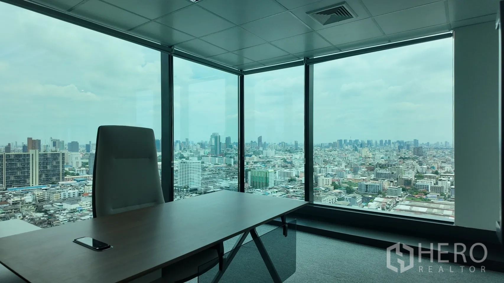 办公室 for rent in Din Daeng, Bangkok - 拐角主管办公室配有大桌与落地窗，俯瞰城市天际线景观。