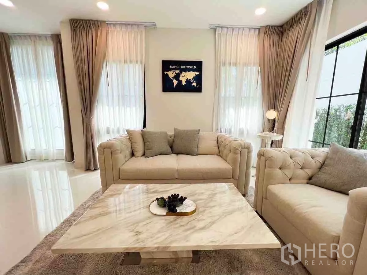 Detached House for rent or sale in Saphan Sung, Bangkok - Cozy lounge corner with beige sofas and marble table by black-framed windows