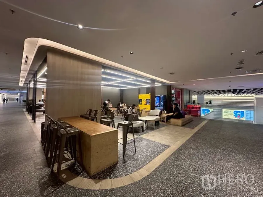 零售空间 出租 - 购物中心内的现代零售休闲区，设有吧台高脚桌、LED网格灯、售货机与抛光地面。