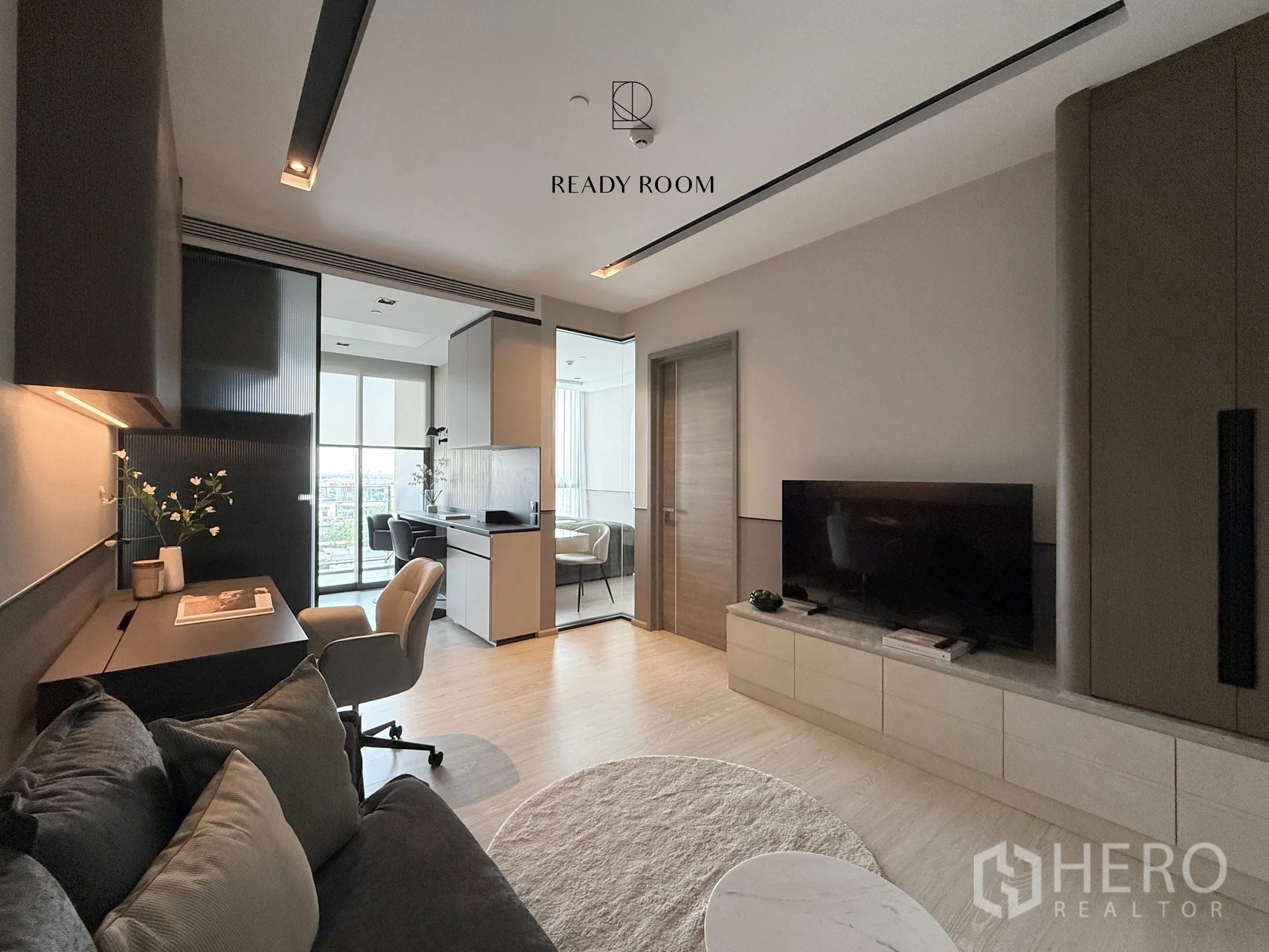Condominium for rent in Khlong Toei, Bangkok - Living room with TV cabinet and doorway to the bedroom and balcony.