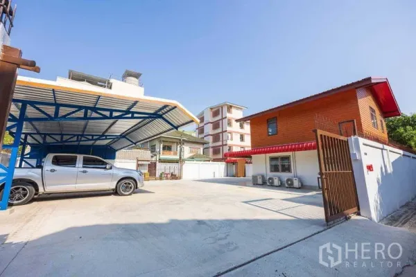 Home Office for rent in Watthana, Bangkok - Wide concrete courtyard with metal carport, gate, and two-storey home office building with air-conditioning units.