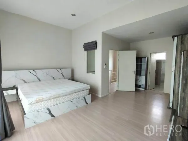 联排别墅 出租在Wang Thonglang, Bangkok - 主卧空间宽敞，仿大理石床架、浅色木地板，连接套内卫生间。