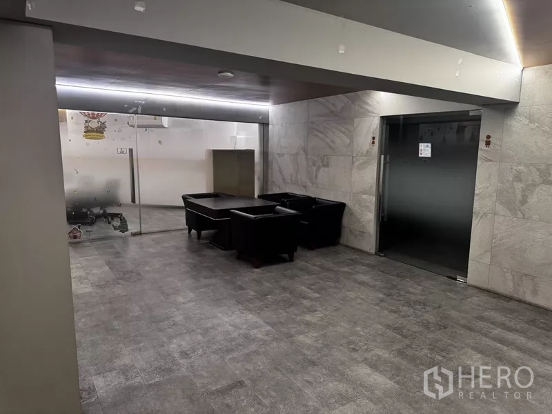 Office Space for rent or sale in Suan Luang, Bangkok - Waiting lounge with black leather sofas next to a glass meeting room and elevator entrance.