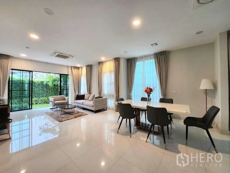 Detached House for rent in Saphan Sung, Bangkok - Living area opening to the garden via black-framed sliding doors beside a contemporary dining table.