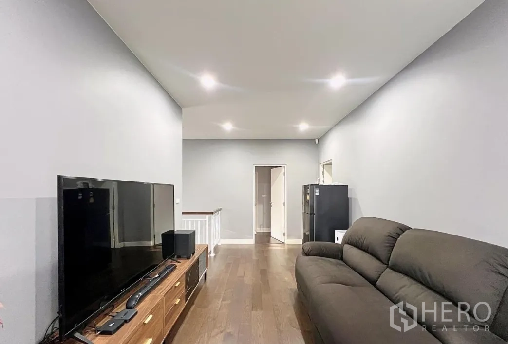 บ้าน ให้เช่าหรือขายในLam Luk Ka, Pathum Thani - ห้องนั่งเล่นชั้นบน ทีวี โซฟา และพื้นไม้ ใกล้โถงบันได