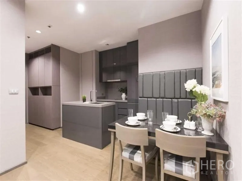 Condominium for rent in Bang Rak, Bangkok - Dining corner with padded wall bench beside a modern grey kitchen with island and ample storage.