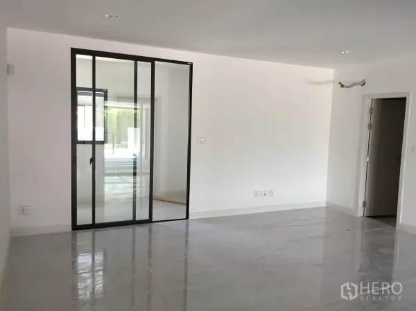 Townhouse for rent in Saphan Sung, Bangkok - Bright living area with white walls, recessed lighting and a large black-frame glass sliding door.