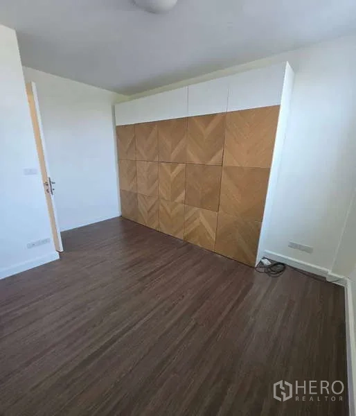 Townhouse for sale in Watthana, Bangkok - Bedroom featuring a built-in chevron wood wardrobe and dark wood flooring.