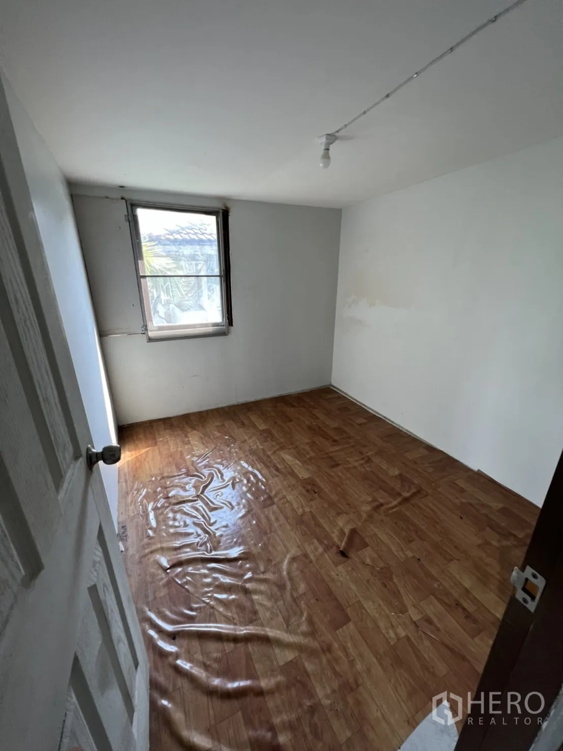 Home Office for rent in Watthana, Bangkok - Compact upstairs room with window and damaged vinyl flooring.