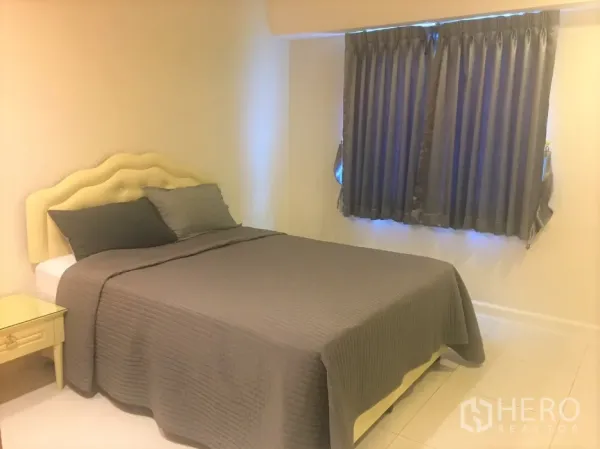 Condominium for rent in Watthana, Bangkok - Cozy bedroom with upholstered headboard, double bed, bedside table, and grey curtains.
