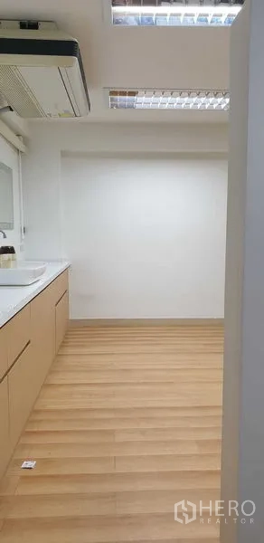 零售空间 出租在Chatuchak, Bangkok - 整洁茶水间，浅木色柜体、水槽、木地板与嵌入式空调。