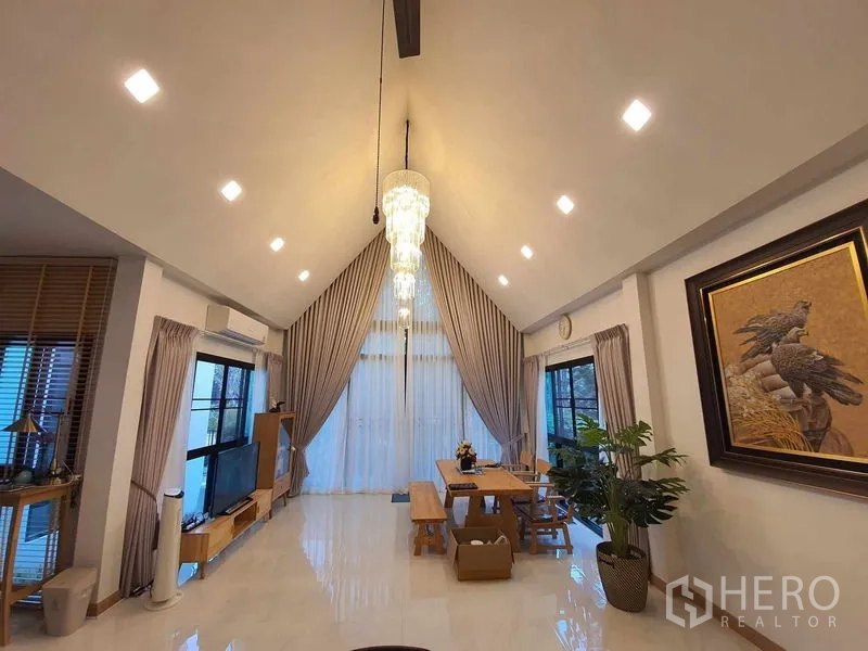 Detached House for sale in Bang Khun Thian, Bangkok - Double-height living space with statement chandelier, curtains and media area.