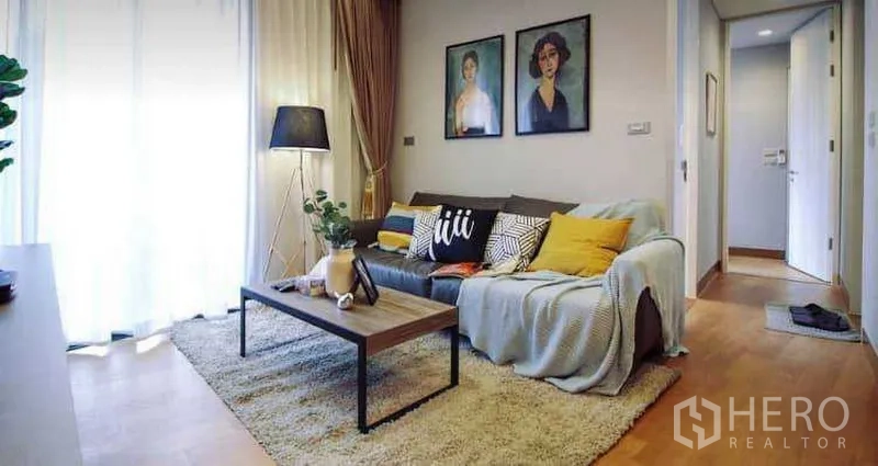 คอนโด ให้เช่าหรือขายในKhlong Toei, Bangkok - ห้องนั่งเล่นอบอุ่น โซฟา โต๊ะกาแฟ โคมไฟตั้งพื้น ผ้าม่านโปร่ง และทางเดินไปยังโซนห้องนอน