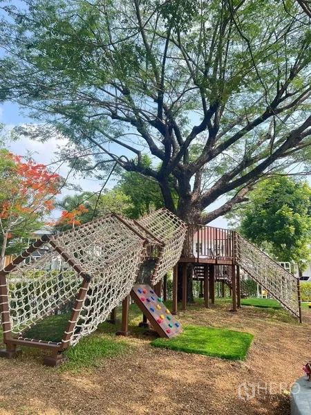 Detached House for rent - Children’s playground with rope tunnels and slides under a large tree on green lawn.