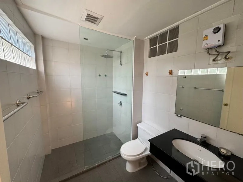 Condominium for rent in Yan Nawa, Bangkok - Bathroom with glass-enclosed rain shower, vanity and toilet.
