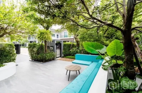 独立式住宅 出租 - 绿意花园露台，内置蓝色长椅与茶几，私密树篱环绕。