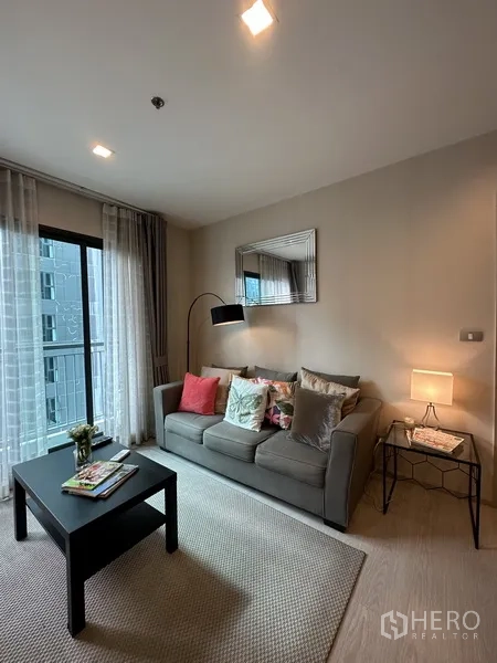 คอนโด ให้เช่าหรือขายในKhlong Toei, Bangkok - มุมนั่งเล่นอบอุ่น มีโซฟา โต๊ะกลาง โคมไฟยืน และกระจกบานเลื่อนออกระเบียง