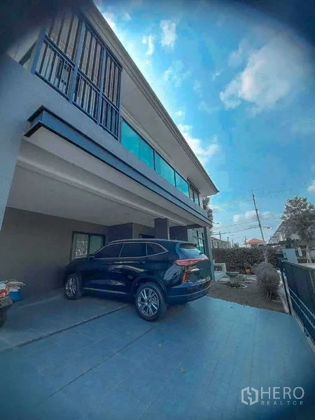 Detached House for rent in Bang Bo, Samut Prakan - Covered carport for two vehicles with SUV parked beneath the second-floor balcony.