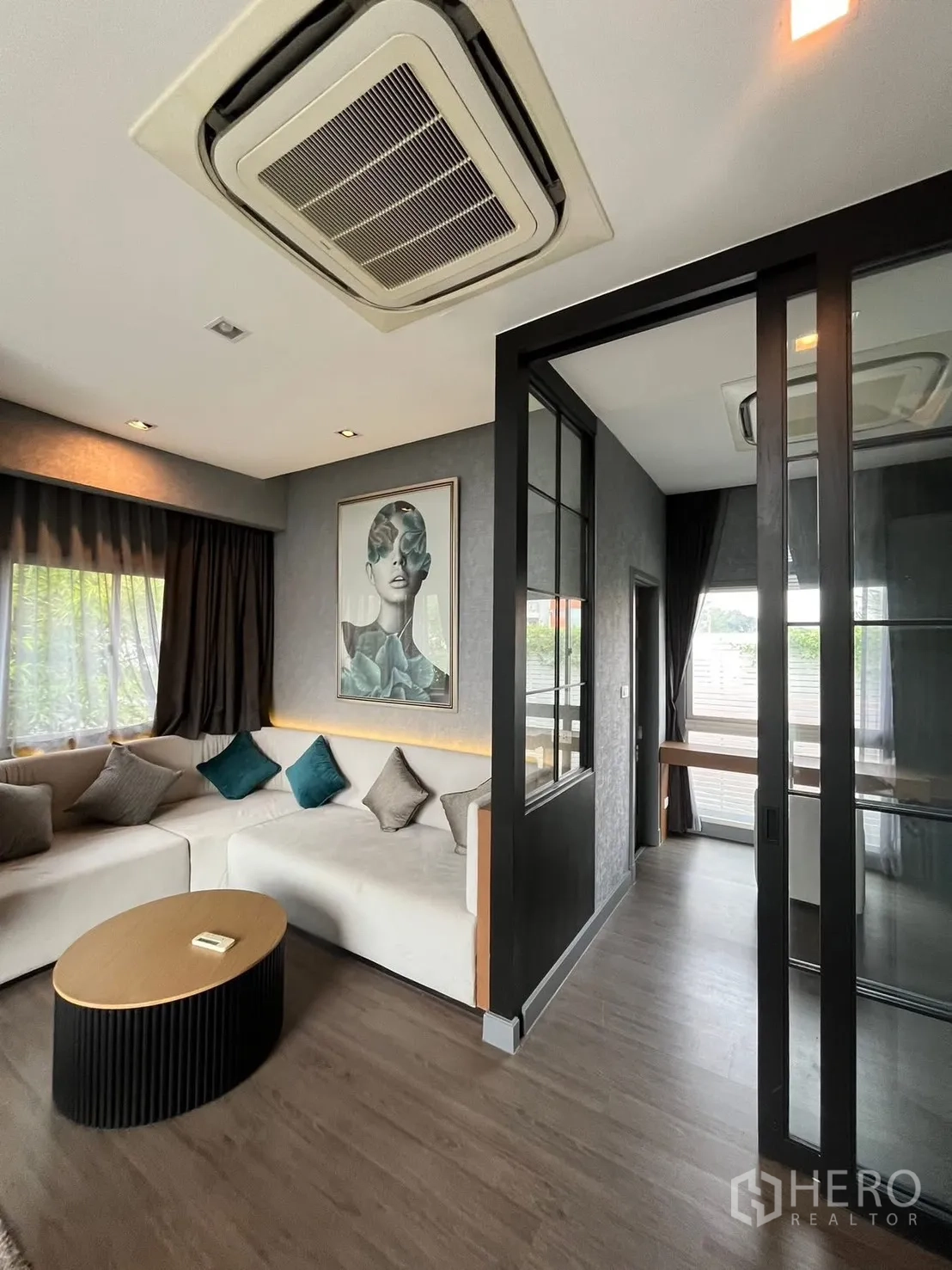 独栋房屋 for rent or sale in Bueng Kum, Bangkok - 家庭起居室配转角沙发、茶几与玻璃隔断的书房。