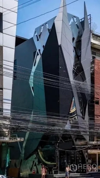 อาคารพาณิชย์ ให้เช่าในKhlong Toei, Bangkok - ด้านหน้าตึกแถวดีไซน์ล้ำ ผนังกระจกโทนเข้มและแผงรูปทรงเหลี่ยมในกรุงเทพฯ