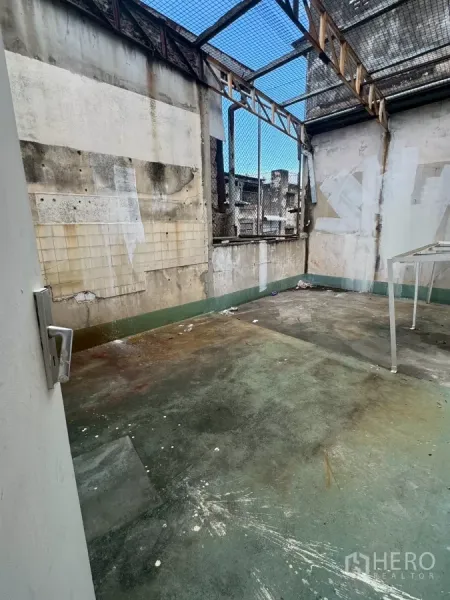 Shophouse for rent in Samphanthawong, Bangkok - Open rooftop terrace with mesh cover and weathered walls.