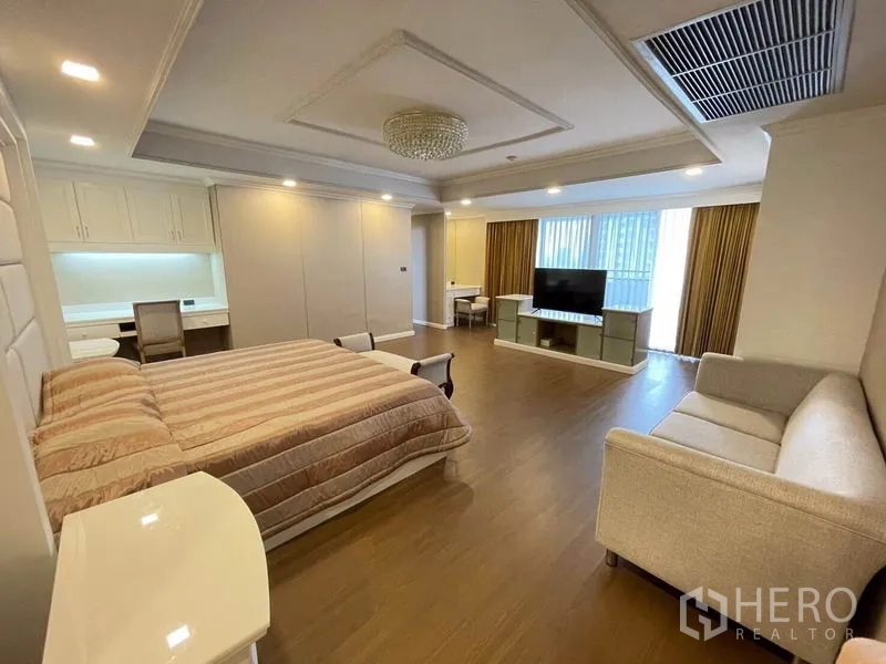 Condominium for rent in Watthana, Bangkok - Master bedroom with king bed, sofa, work desk, and TV cabinet by large windows.