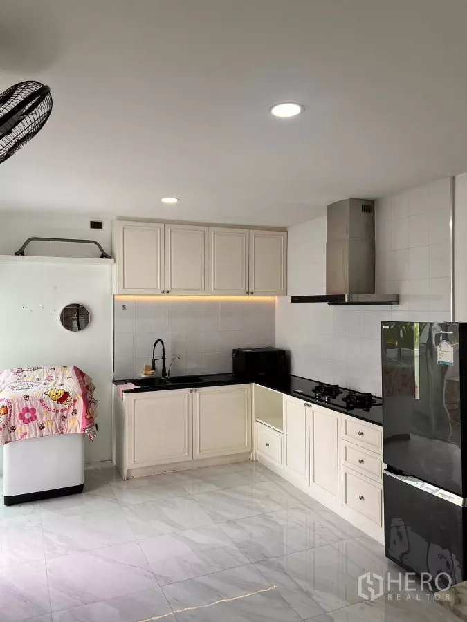 บ้าน ให้เช่าในLat Krabang, Bangkok - ครัวรูปตัวแอล ตู้บิวท์อินสีขาว เตาแก๊ส เครื่องดูดควัน และท็อปสีดำ
