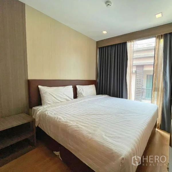 คอนโด ให้เช่า - ห้องนอนมุมหน้าต่างใหญ่ม่านทึบและเตียง