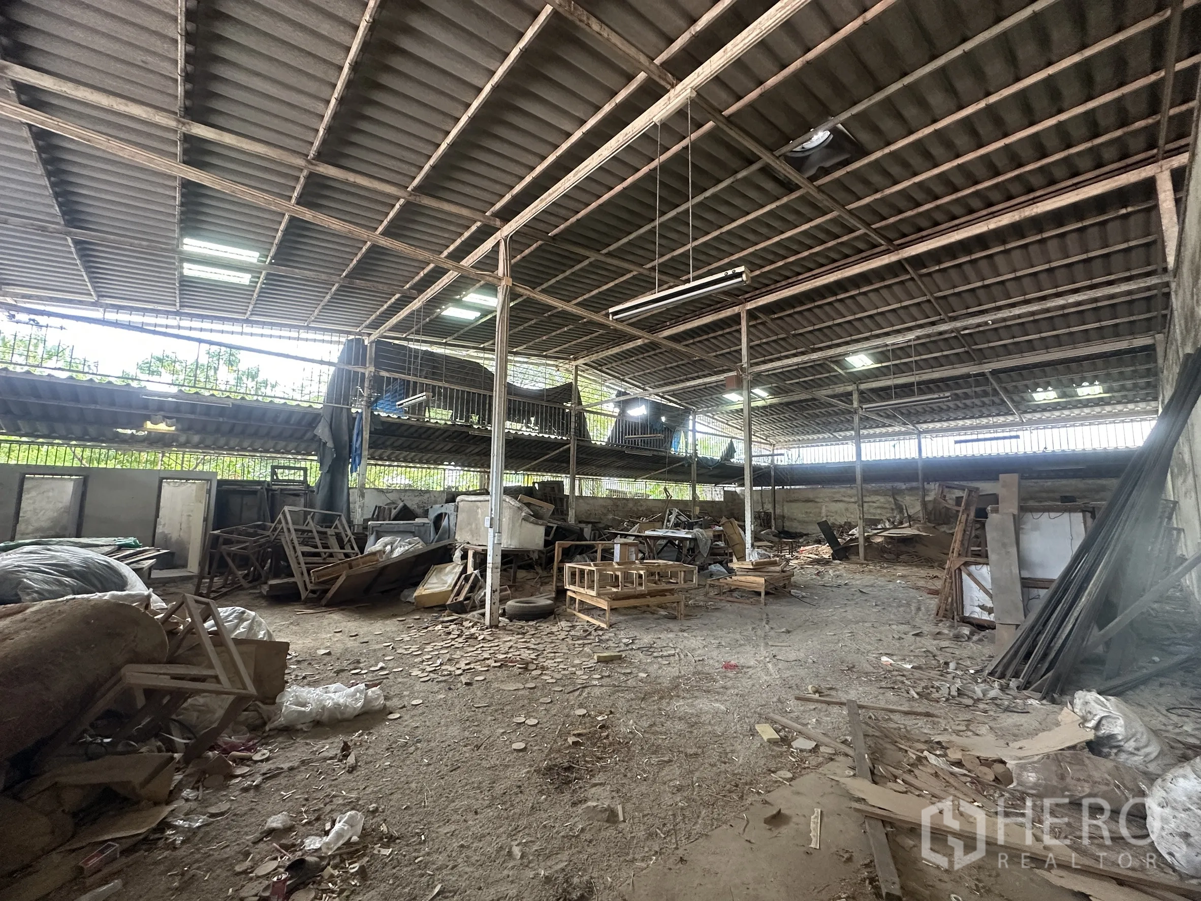 Warehouse for rent in Lam Luk Ka, Pathum Thani - Covered storage zone with mezzanine platform and materials on the ground.