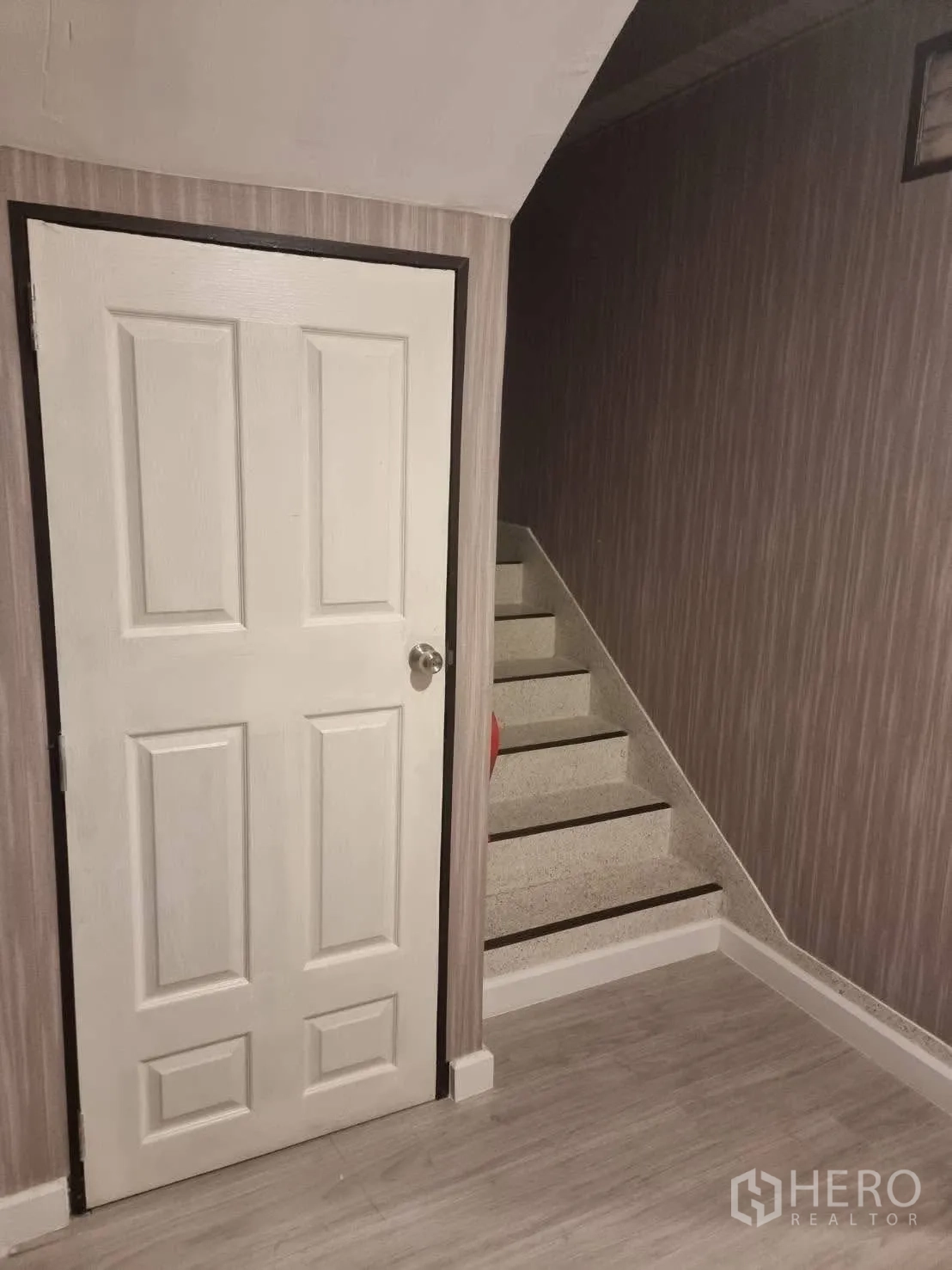 Townhouse for rent in Din Daeng, Bangkok - Under-stair storage door beside steps with textured wall covering.