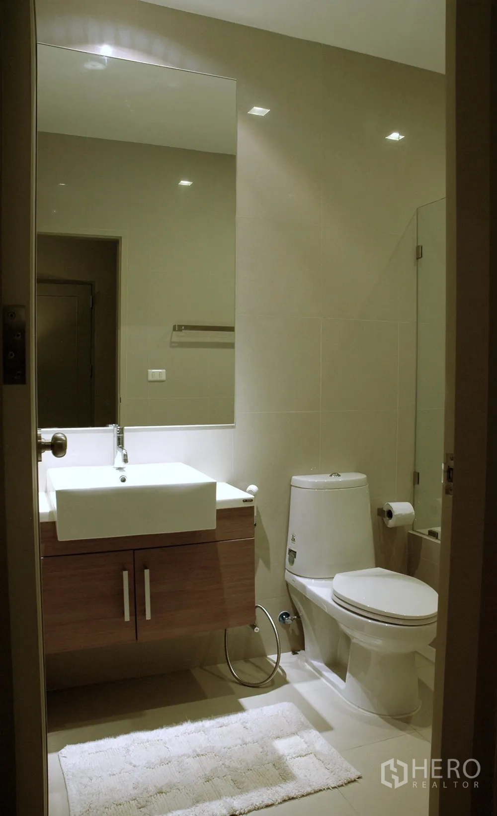 Condominium for rent in Watthana, Bangkok - Modern vanity with square basin, large mirror and toilet in a tiled bathroom.