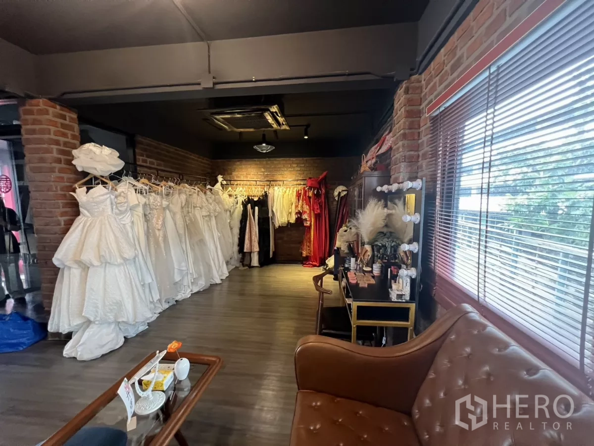 零售空间 出租在Watthana, Bangkok - 化妆角落配灯镜与沙发，旁边为婚纱挂架。