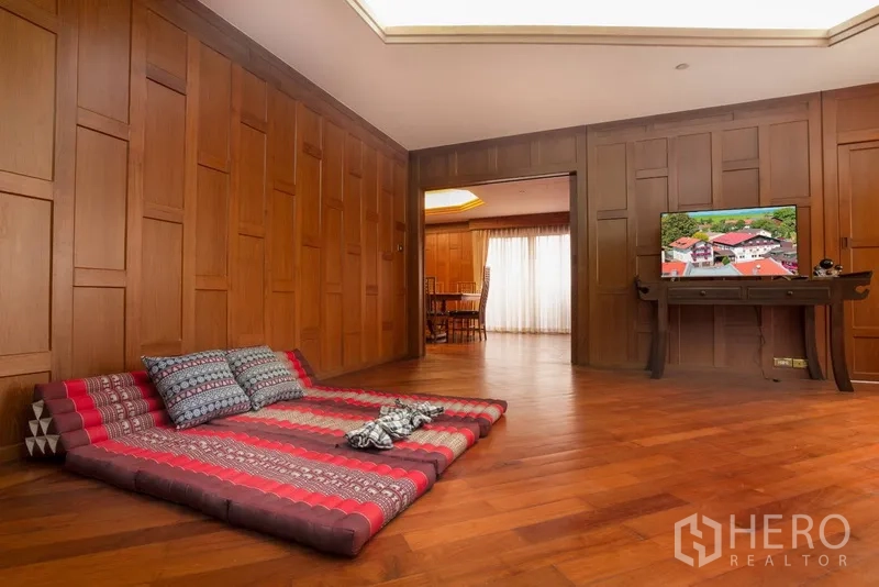 Condominium for rent or sale in Ratchathewi, Bangkok - Cozy living area with Thai floor mattress, TV console and full wood paneling.