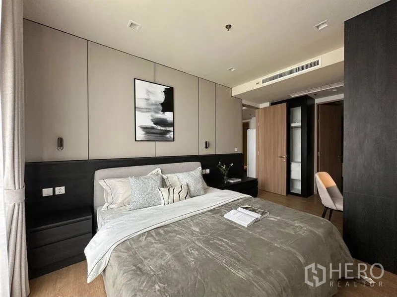 Condominium for rent in Watthana, Bangkok - Serene bedroom with gray bedding, paneled feature wall and built-in wardrobes.