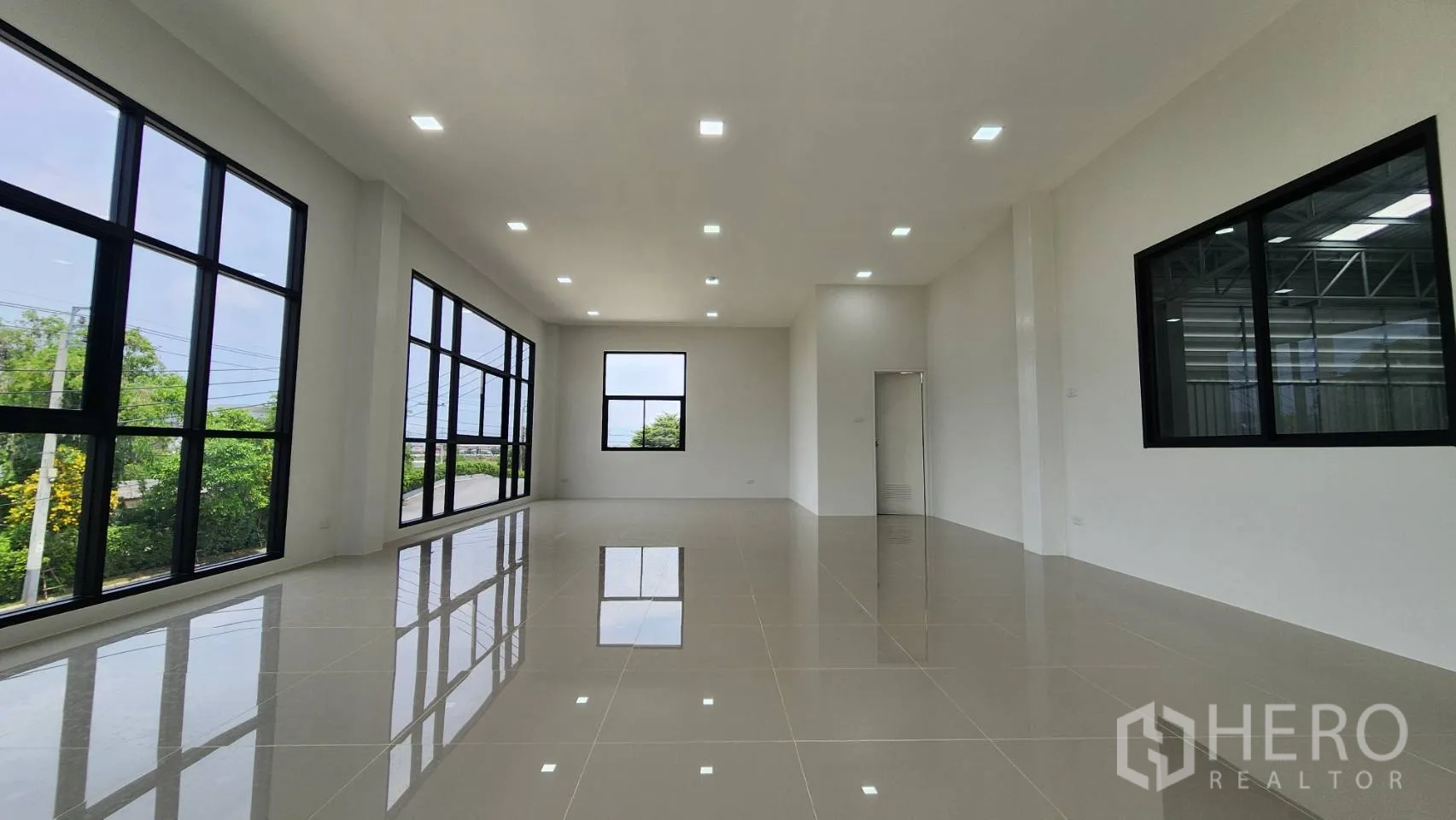 Factory for rent or sale in Bang Bo, Samut Prakan - Bright upper‑floor office with large black‑framed windows and glossy tiled flooring.