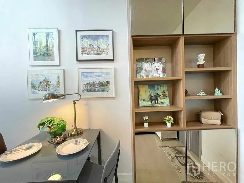 Condominium for sale in Huai Khwang, Bangkok - Cozy dining corner with two-seat table, wall art and wooden display shelves.