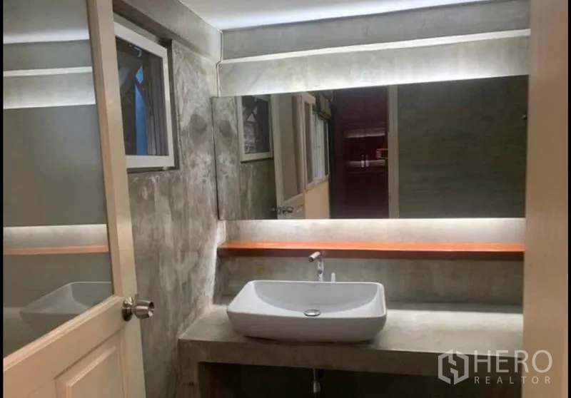 Detached House for rent in Wang Thonglang, Bangkok - Modern bathroom with large backlit mirror and vessel sink on a concrete counter.
