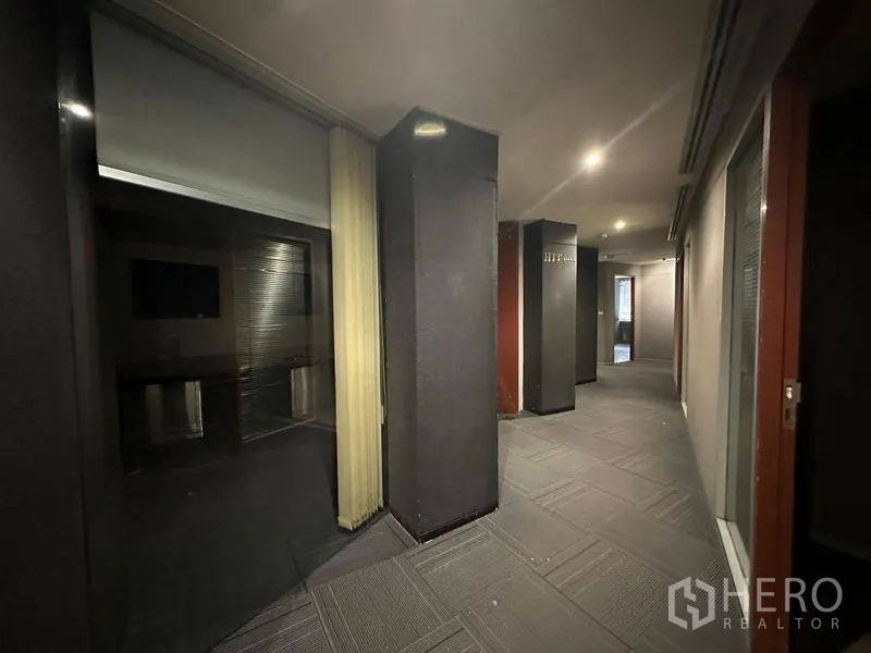 Office Space for rent in Watthana, Bangkok - Dim corridor with pillars, glass partitions and recessed lights