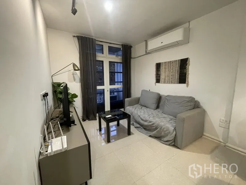 สำนักงานที่บ้าน ให้เช่าหรือขายในWatthana, Bangkok - ห้องนั่งเล่นอบอุ่น โซฟา ทีวี แอร์แบบติดผนัง และประตูกระจกออกระเบียง