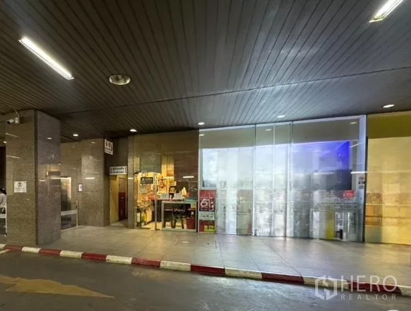 零售空间 出租 - 玻璃店面位于有顶走道下，花岗岩立柱与外部照明清晰可见。