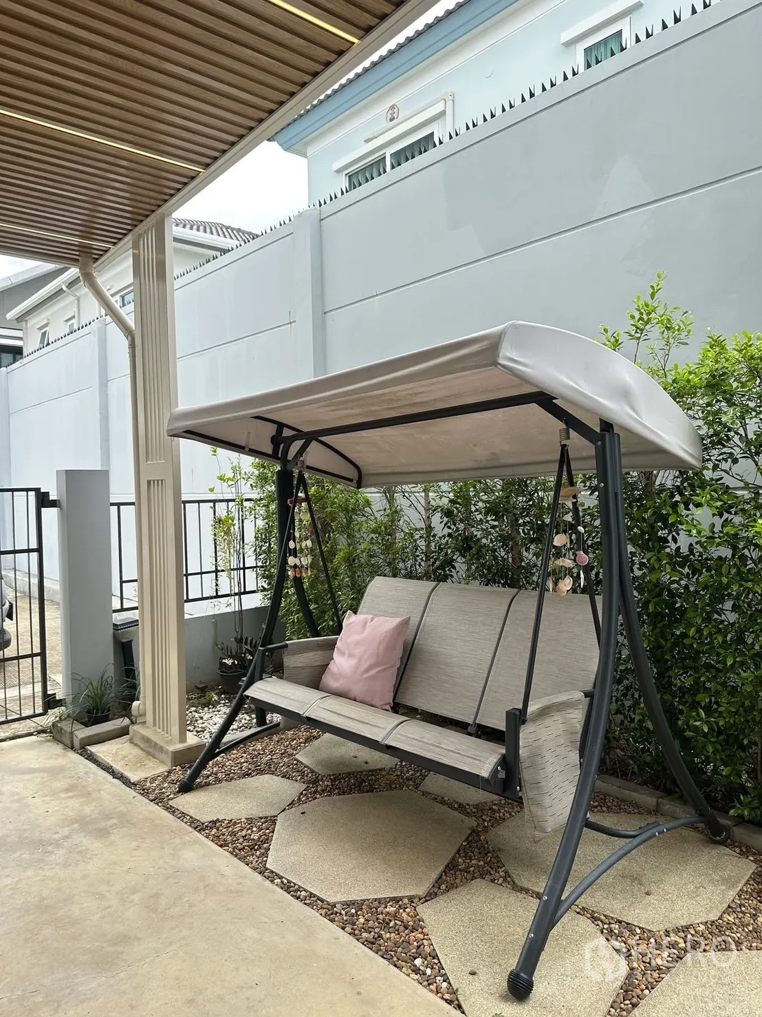 联排别墅 for rent in Prawet, Bangkok - 前院庭院秋千位于棚下，旁有绿植。