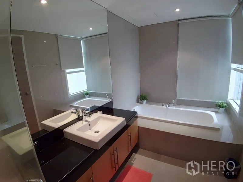 公寓 出租在Watthana, Bangkok - 主卫设长浴缸、宽台面洗手盆与大镜面，自然采光柔和。