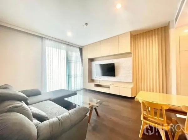 Condominium for rent in Watthana, Bangkok - Living area with floor-to-ceiling windows, balcony access and TV cabinetry.