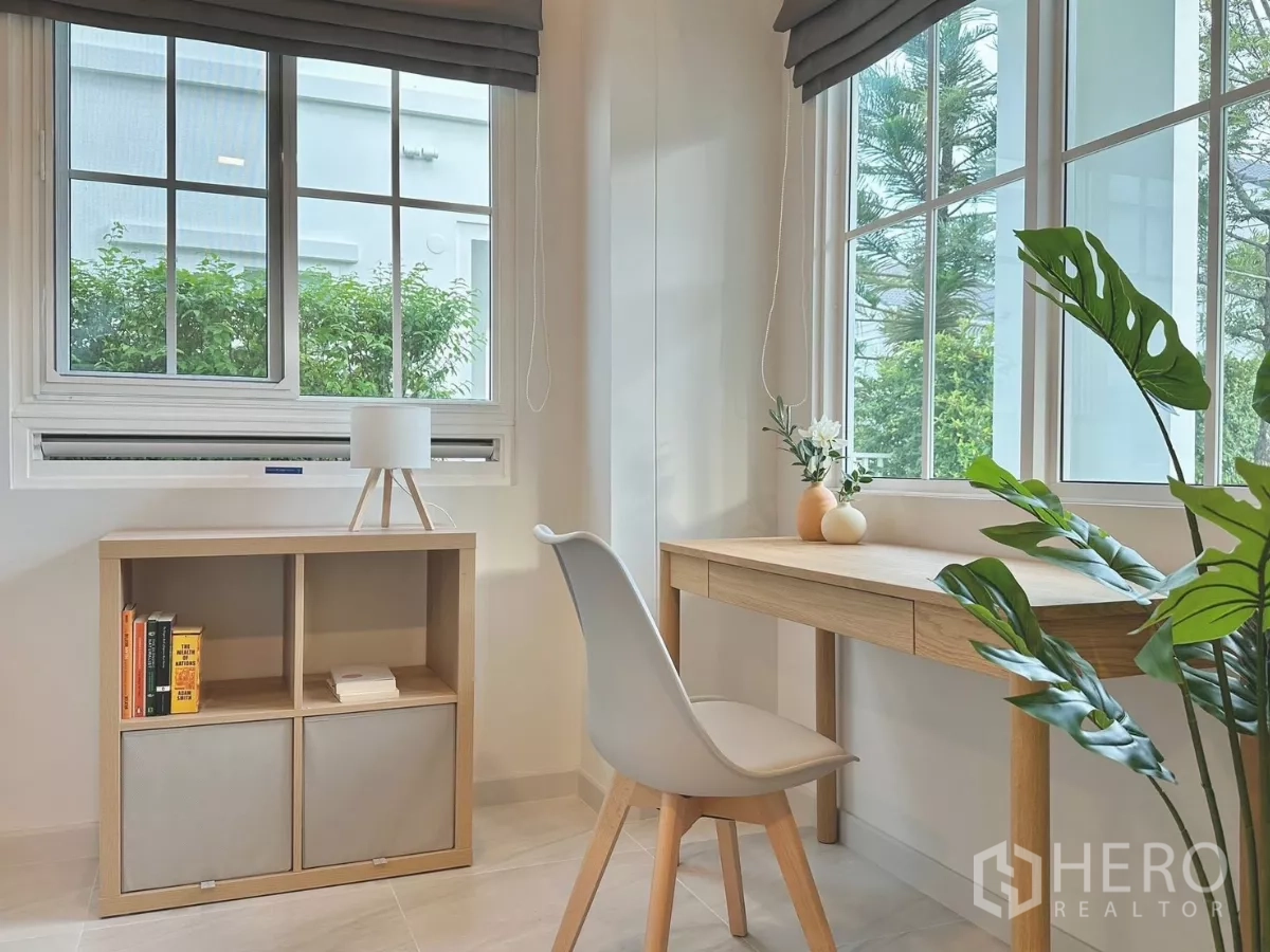 独立式住宅 出租在Bang Phli, Samut Prakan - 家庭起居室以灰色沙发为中心，厨房在后方，两侧为花园。