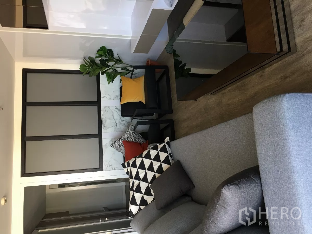 Condominium for rent or sale in Watthana, Bangkok - Seating corner in the living room with sofa, armchairs and a decorative partition.